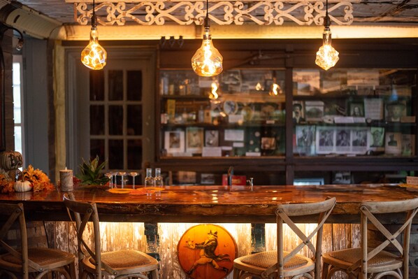 Un rústico espacio de bar con sillas de madera, una barra y lámparas colgantes.