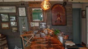 Una barra de madera larga con un candelabro antiguo, cuadros en las paredes y un cartel que dice "The Back Porch Bar".