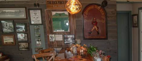 Una barra de madera larga con un candelabro antiguo, cuadros en las paredes y un cartel que dice "The Back Porch Bar".
