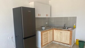 Une cuisine avec un réfrigérateur noir, des armoires en bois, un plan de travail en granit et un évier.