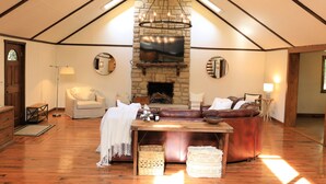 Un salon chaleureux avec une cheminée en pierre, des canapés en cuir et une table basse en bois.