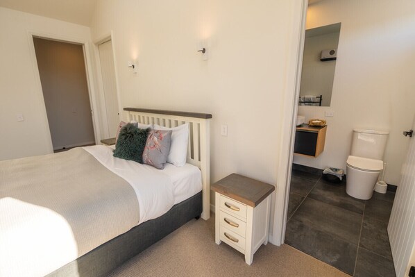 A bedroom with a bed, bedside table, and a small cabinet.