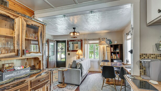 A cozy living room with a fireplace, a dining area, and a kitchen. - Family-Friendly Cottage: Walk to Lake Access! (Prudenville)
