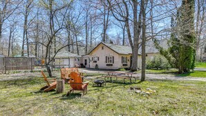 A house with a front yard, picnic tables, and a wooden chair. - Family-Friendly Cottage: Walk to Lake Access! (Prudenville)