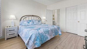 Un dormitorio con cama, mesitas de noche, ventilador de techo y puertas blancas.