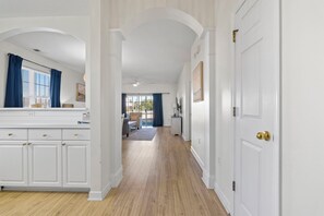 A hallway with white walls, wooden flooring, and a white door with a brass handle. - Ground Floor 2BR Barefoot Resort Condo in Ironwood (North Myrtle Beach)
