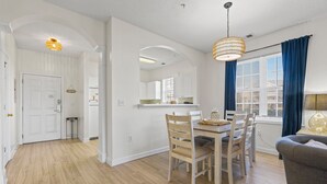 Una cocina moderna con armarios blancos, una mesa de comedor con sillas y una araña.