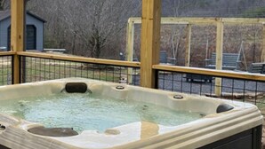 A hot tub in an outdoor setting with a wooden deck and a metal fence. - 5 Bedrooms Pool Theater Arcade Firepit (Sevierville)