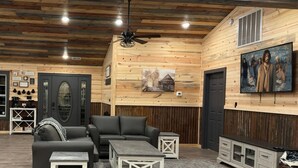 A cozy cabin interior with a sectional sofa, a coffee station, and a mounted painting. - 5 Bedrooms Pool Theater Arcade Firepit (Sevierville)