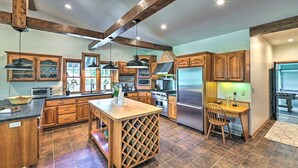 A spacious kitchen with wooden cabinets, a central island with a wine rack, and a built-in stove.