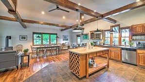 A spacious kitchen with wooden beams, a central island, and large windows.
