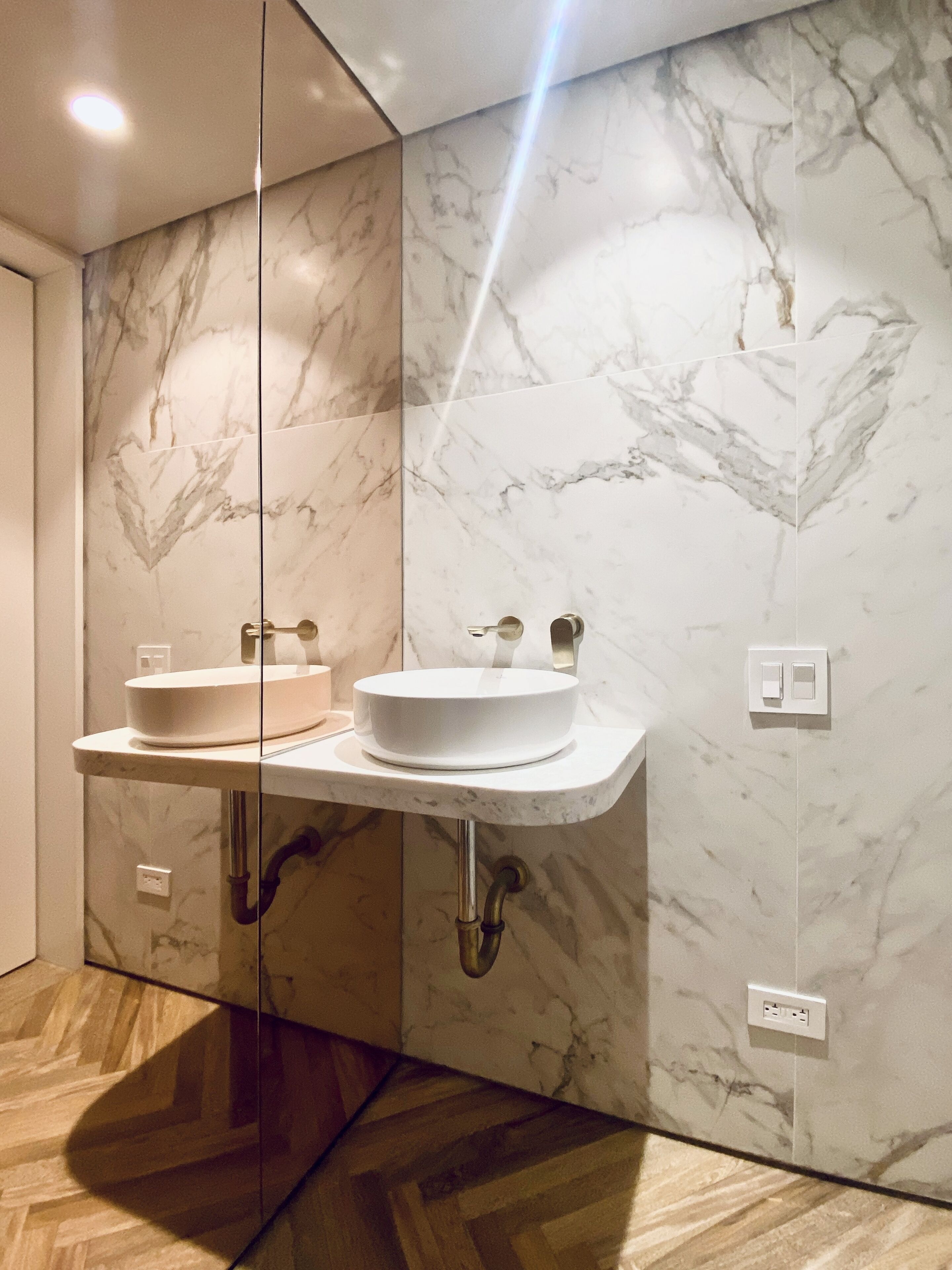 A modern bathroom with a marble wall and two sinks.
