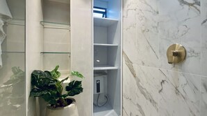 A modern bathroom with a shower enclosure, marble walls, and a potted plant. - Palace by Wynwood House  (Bogotá)