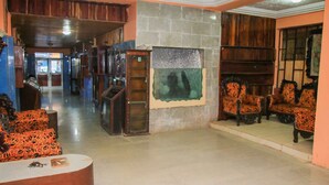A spacious lobby with a stone fireplace, wooden paneling, and patterned armchairs. - Atlanticoast Residence (Bakau)