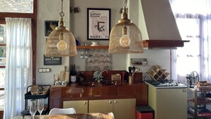 Een keuken met hangende hanglampen, een betegelde spatwand, een houten kast en een raam met gordijnen.
