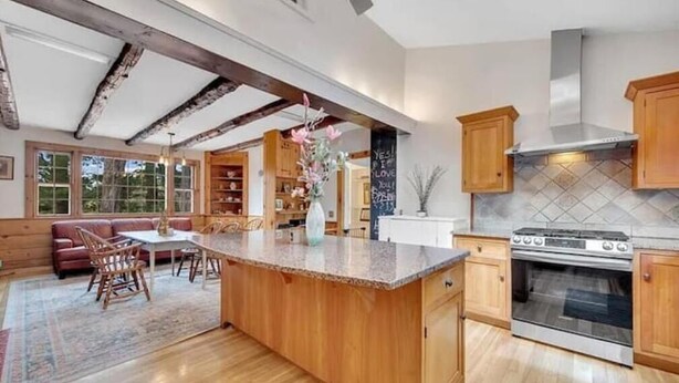 A spacious kitchen with wooden cabinets, a large island, and a stainless steel oven. - Colonial yellowhouse (Newtown)