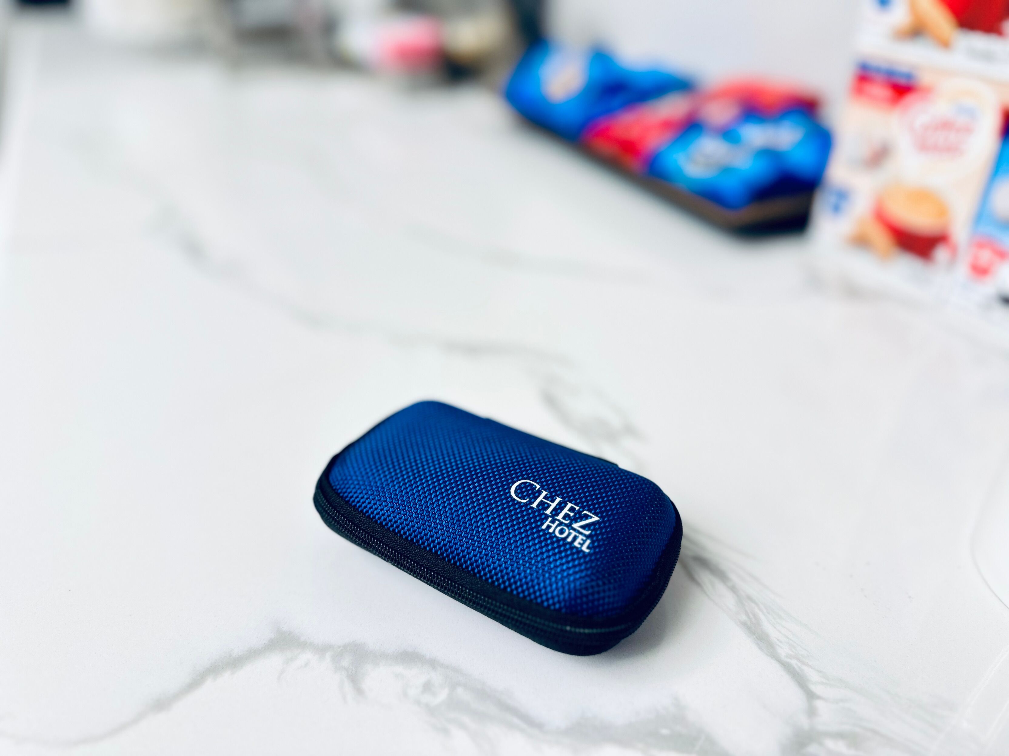 Een blauwe hotelbag met de tekst 'CHIEZ HOTEL' op een witte marmeren ondergrond.