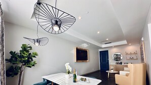 A modern dining area with a white marble table, blue upholstered chairs, and a black pendant light. - Chez Hotel Arlington Heights (Arlington Heights)