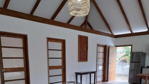 A spacious room with a wooden dining table, white chairs, a woven pendant light, and a view of the outdoors. - Fare Pitate (Paea)