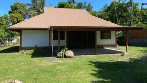 A single-story house with a sloped roof, a covered porch, and a well-maintained lawn. - Fare Pitate (Paea)