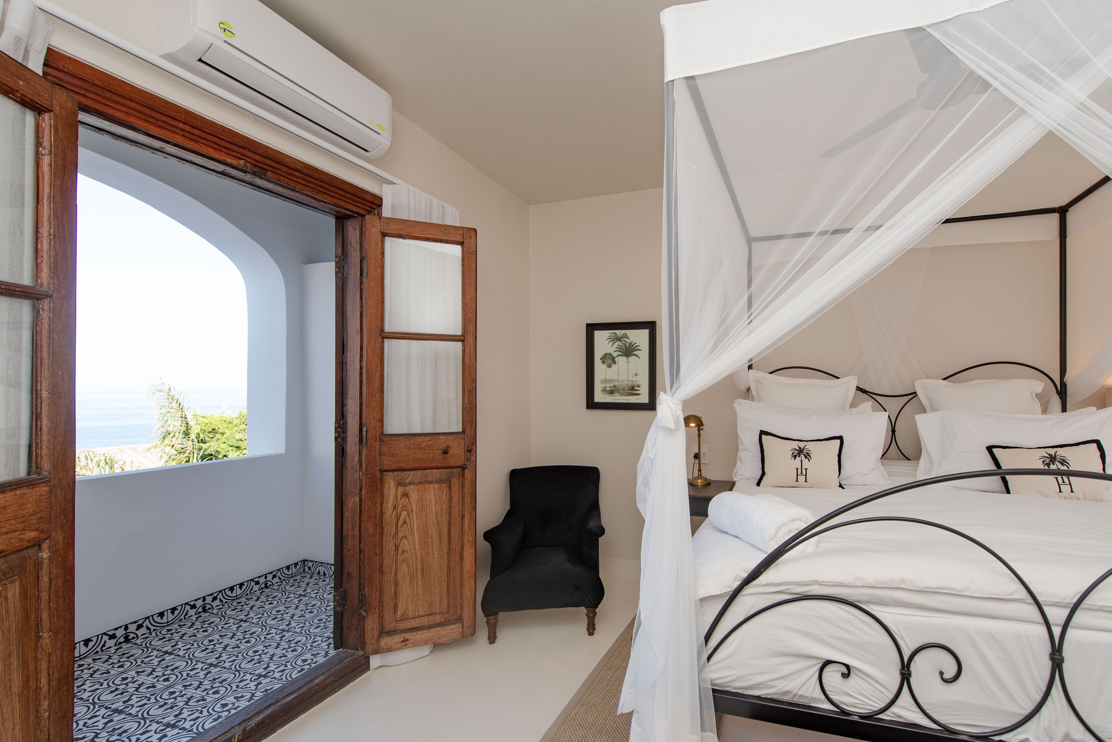 A bedroom with a bed, a chair, and a window with a view.