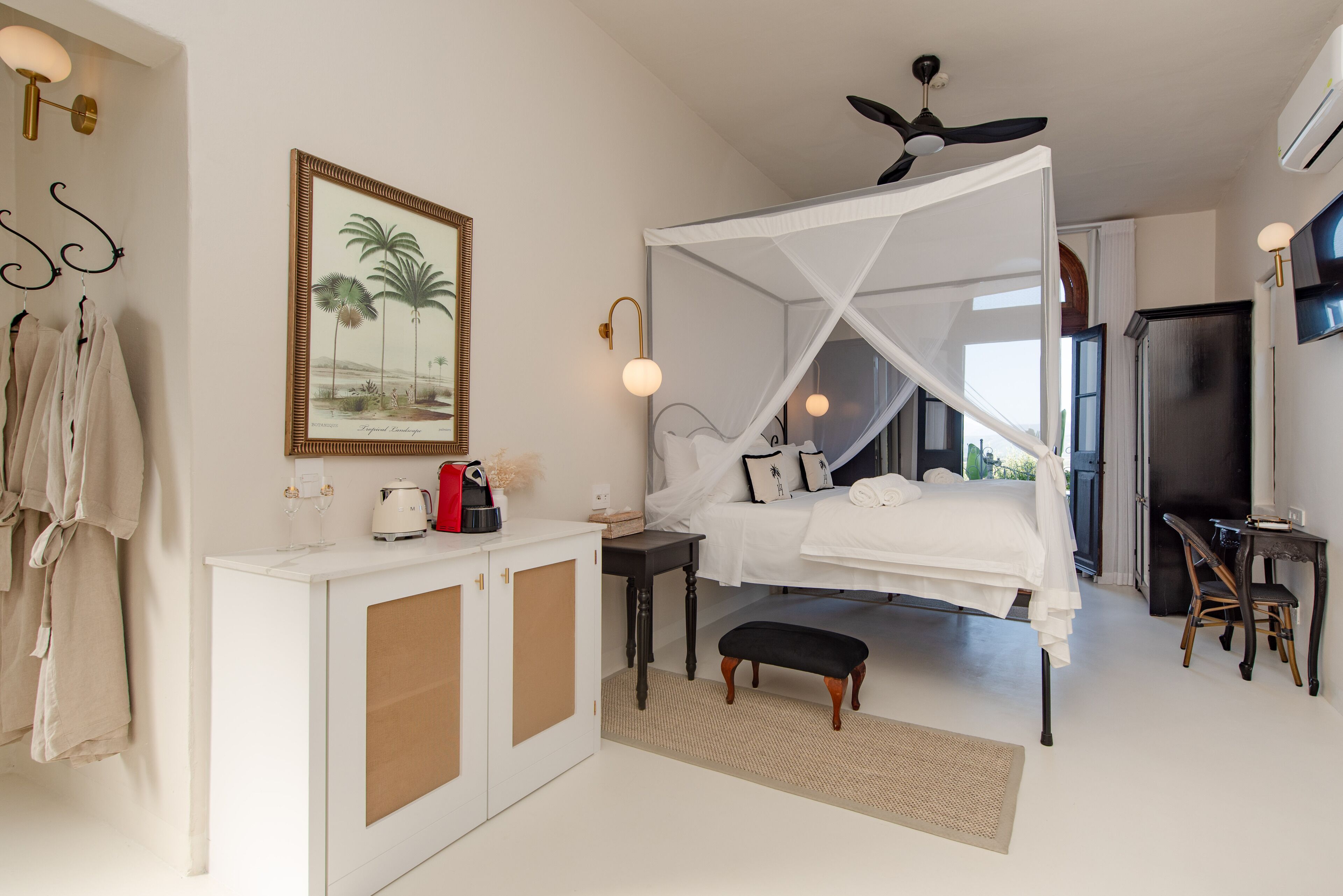 A bedroom with a canopy bed, a white wardrobe, a desk, and a chair.