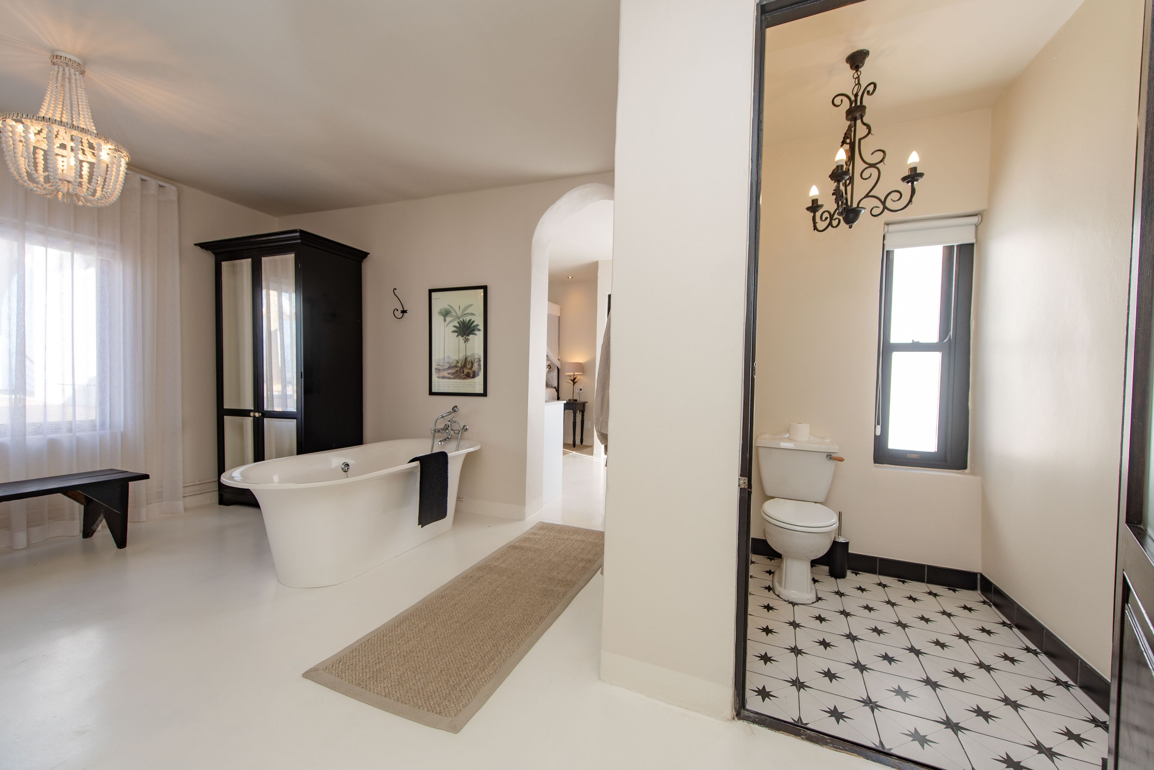 Een ruime badkamer met een vrijstaand bad, een toilet en een wastafelmeubel.