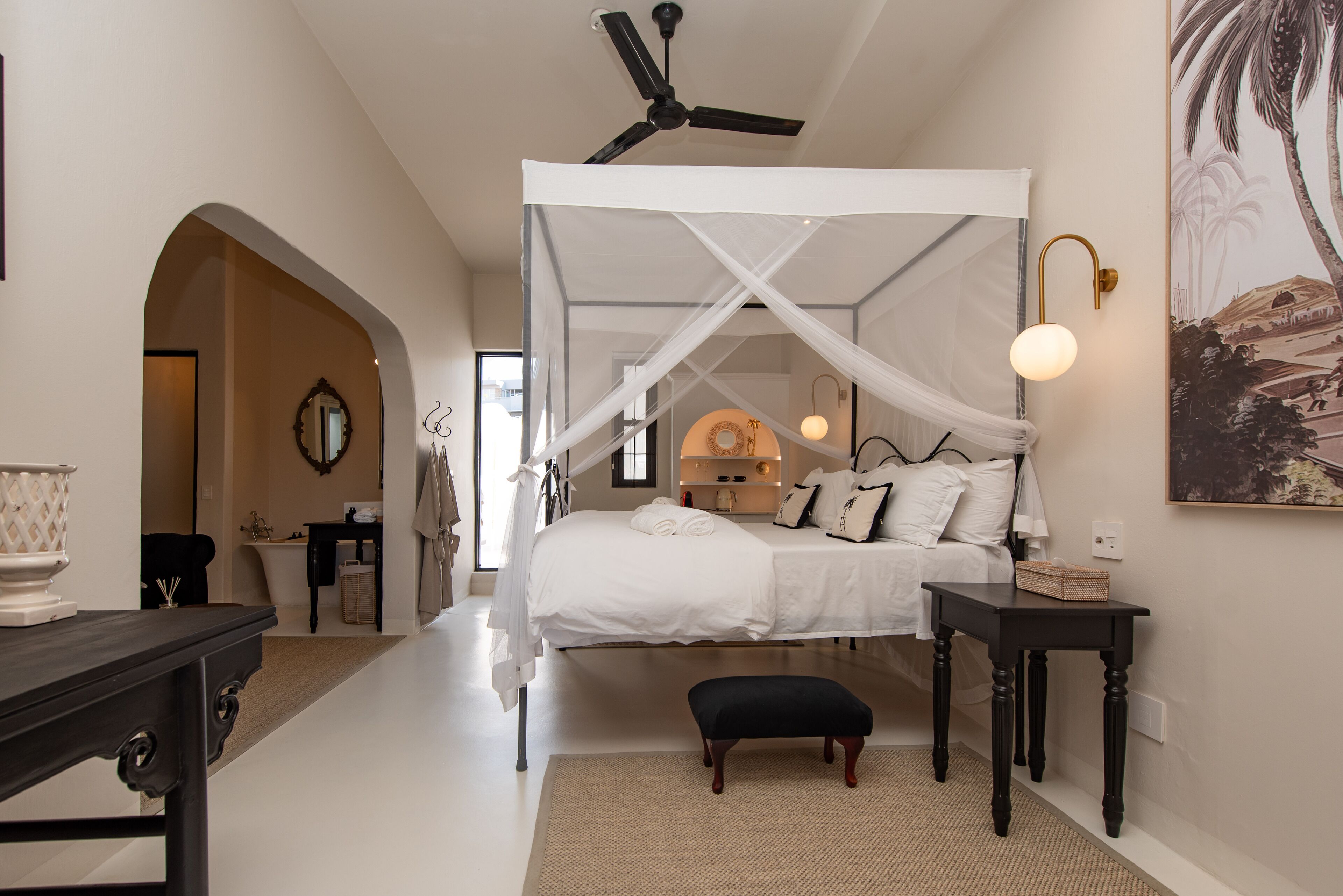 A bedroom with a canopy bed, a ceiling fan, a bedside table, and a nightstand.