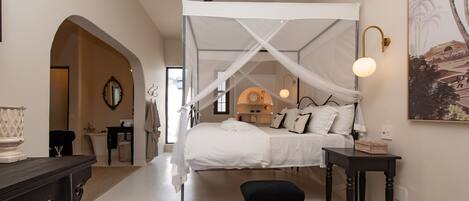 A bedroom with a canopy bed, a ceiling fan, a bedside table, and a nightstand.