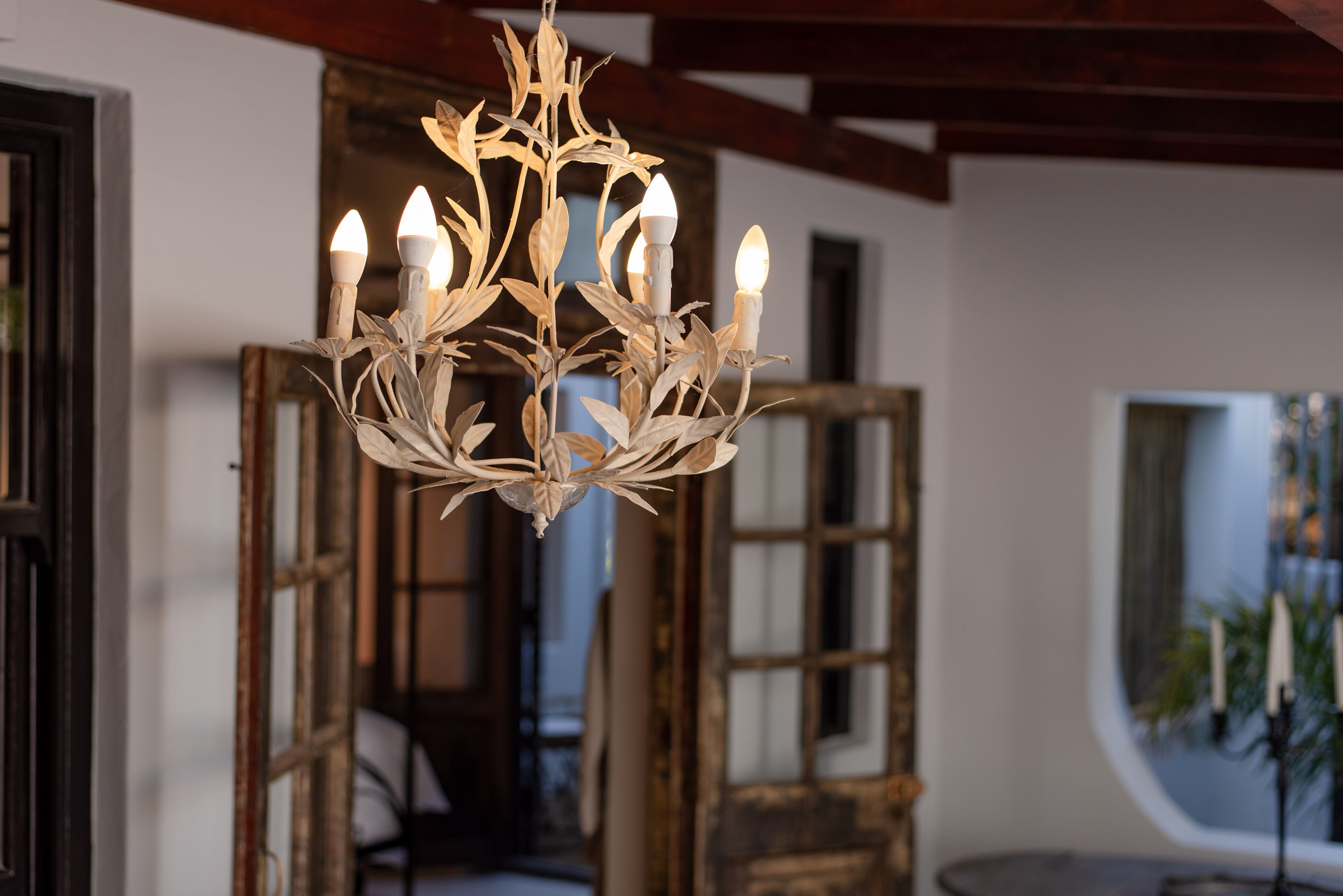 Un lustre doté de plusieurs ampoules, dans une pièce avec des portes en bois et une fenêtre.