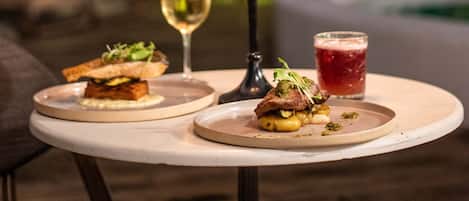 A table with a candle holder, two glasses of beverages, and two plates of food.