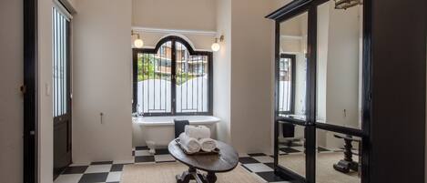 A bathroom with a checkered floor, a round table with towels, a bathtub, and a large mirror.