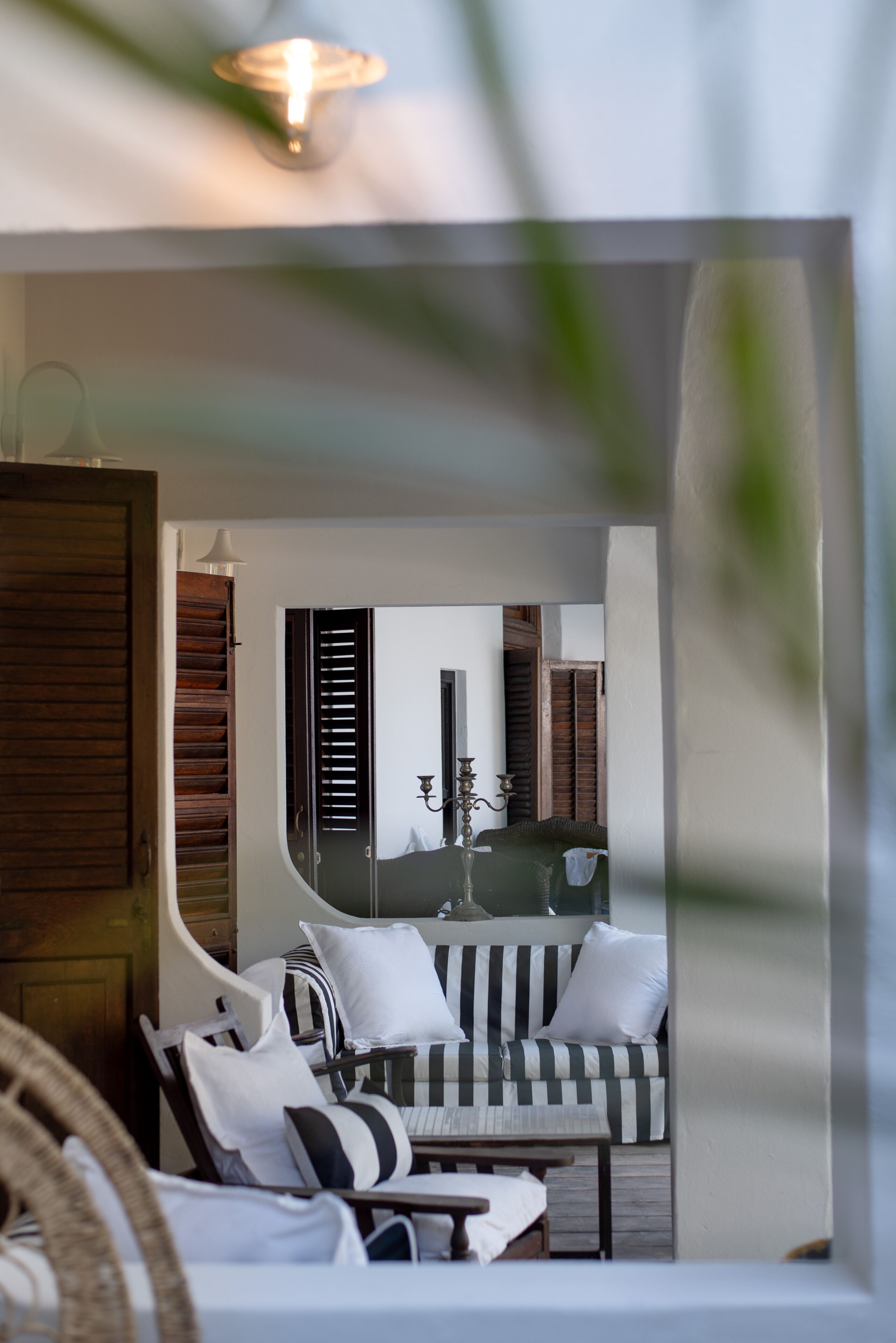 A modern lounge area with a striped sofa, a wooden cabinet, and a mirror reflecting the room.