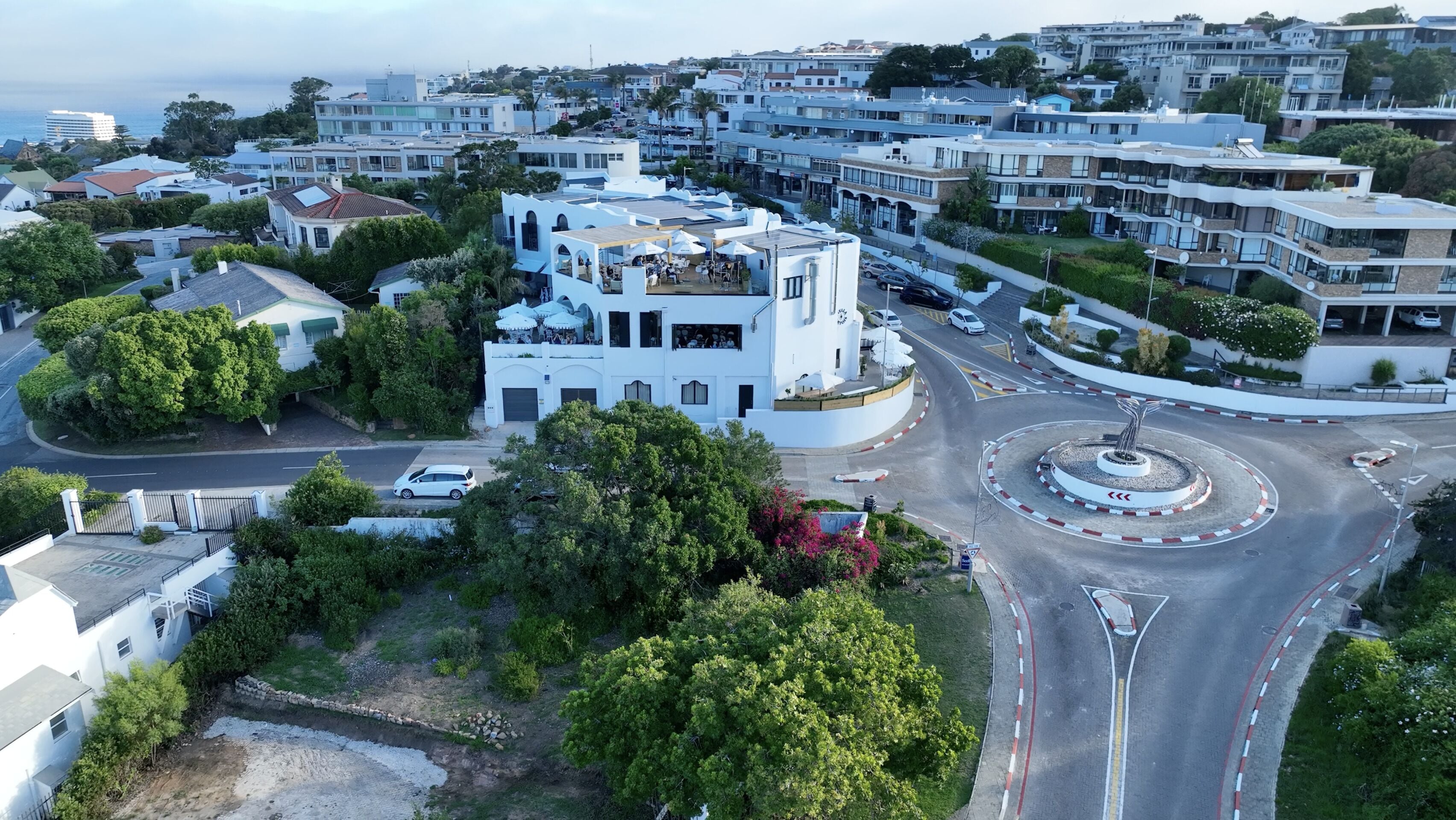 Un bâtiment moderne doté d’une architecture originale, entouré d’une végétation luxuriante et d’un jardin bien entretenu.
