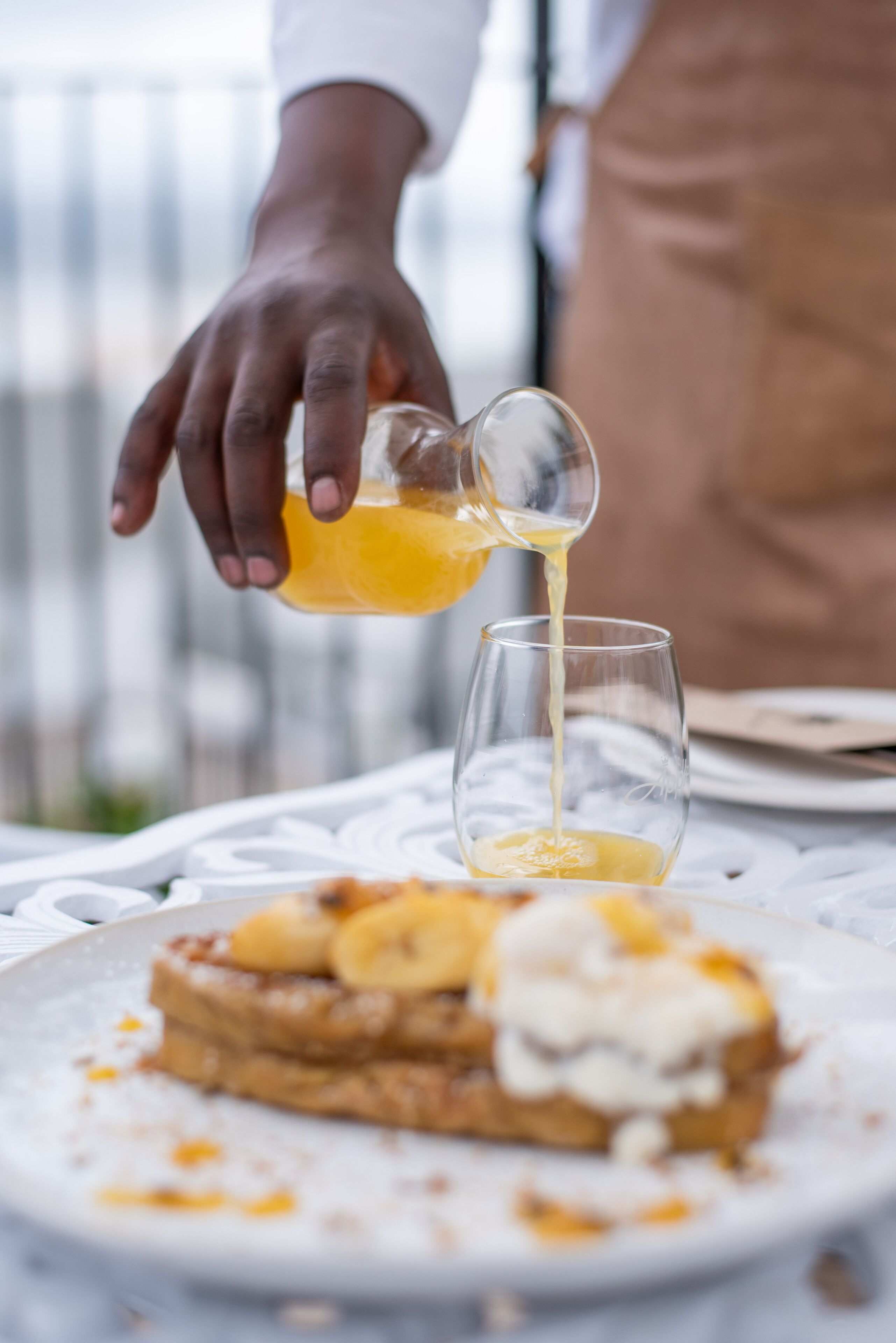 A person pouring orange juice into a glass.