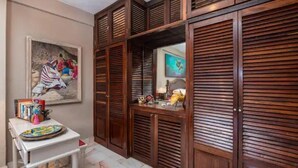A room with wooden louvered closets, a white table with a colorful plate, and a framed painting on the wall. - Paradise Ocean View Condominium in Puerta Vallarta (Puerto Vallarta)