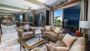 A spacious living room with a large glass door leading to a balcony, a dining area, and a kitchen with a view. - Paradise Ocean View Condominium in Puerta Vallarta (Puerto Vallarta)