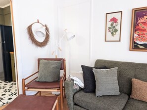 A living room with a wooden chair, a green sofa, and a white lamp.