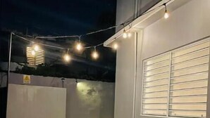 Un espace extérieur aménagé avec des chaises et des guirlandes lumineuses.