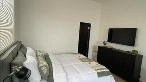 Une chambre à coucher avec un lit, une table de chevet, une télévision et une armoire.