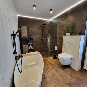 Une salle de bain moderne avec une baignoire sur pieds, une douche à parois de verre et des toilettes.