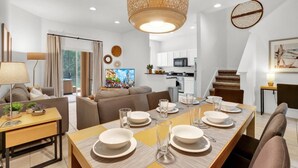 Un salon moderne comprenant un coin repas, une cuisine et un escalier.