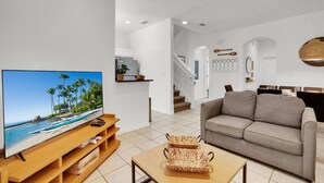 Un salon moderne avec un téléviseur à écran plat, un canapé et une table basse.