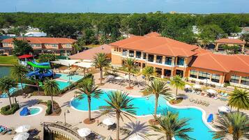 Un resort con una amplia piscina central, varias piscinas más pequeñas y un tobogán de agua.