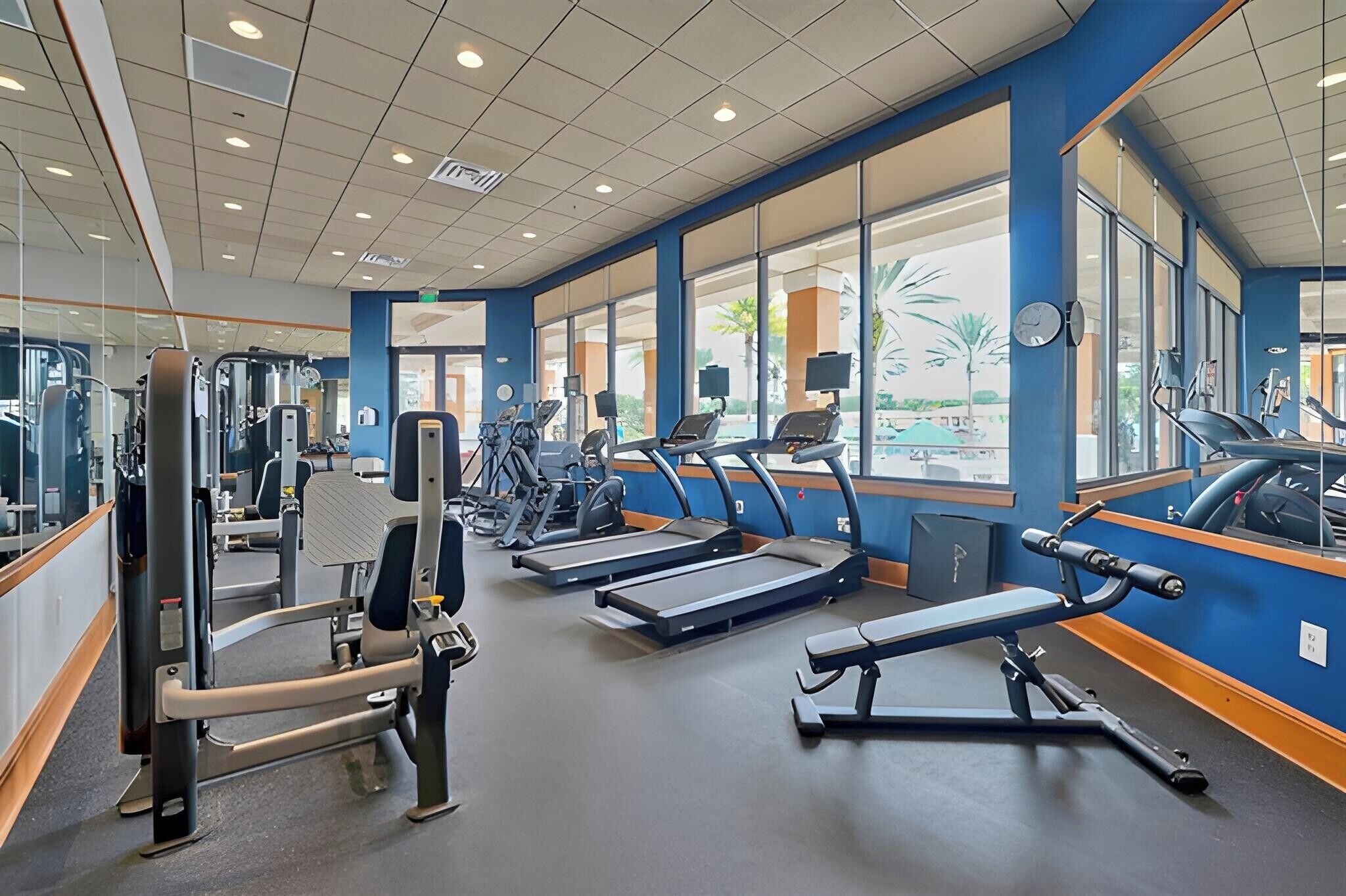 Un gimnasio con cintas de correr, máquinas de pesas y equipo de ejercicio.