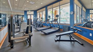 Un gimnasio con cintas de correr, máquinas de pesas y equipo de ejercicio.