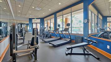 Un gimnasio con cintas de correr, máquinas de pesas y equipo de ejercicio.
