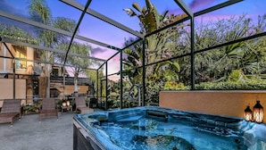 A hot tub area with a view of tropical plants and a building in the background.