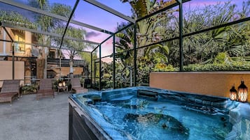 A hot tub area with a view of tropical plants and a building in the background.