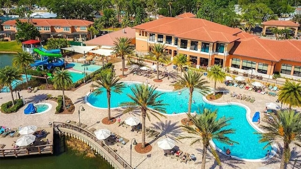 A resort with multiple swimming pools, palm trees, and a large building with a red roof.